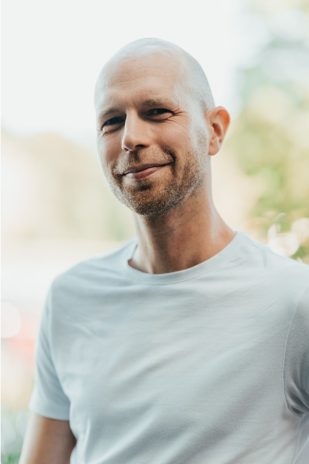 Markus Waltenspiel im hellen T-Shirt, leicht lächelnd, vor weichem hellem Hintergrund.